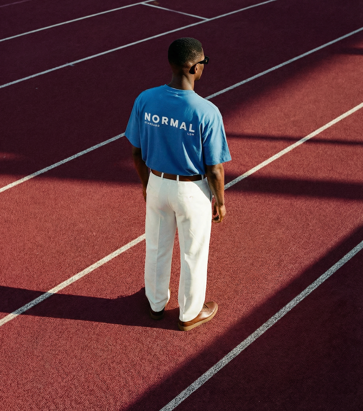 Man wearing blue Normal Standard t-shirt on running track representing modern men’s streetwear