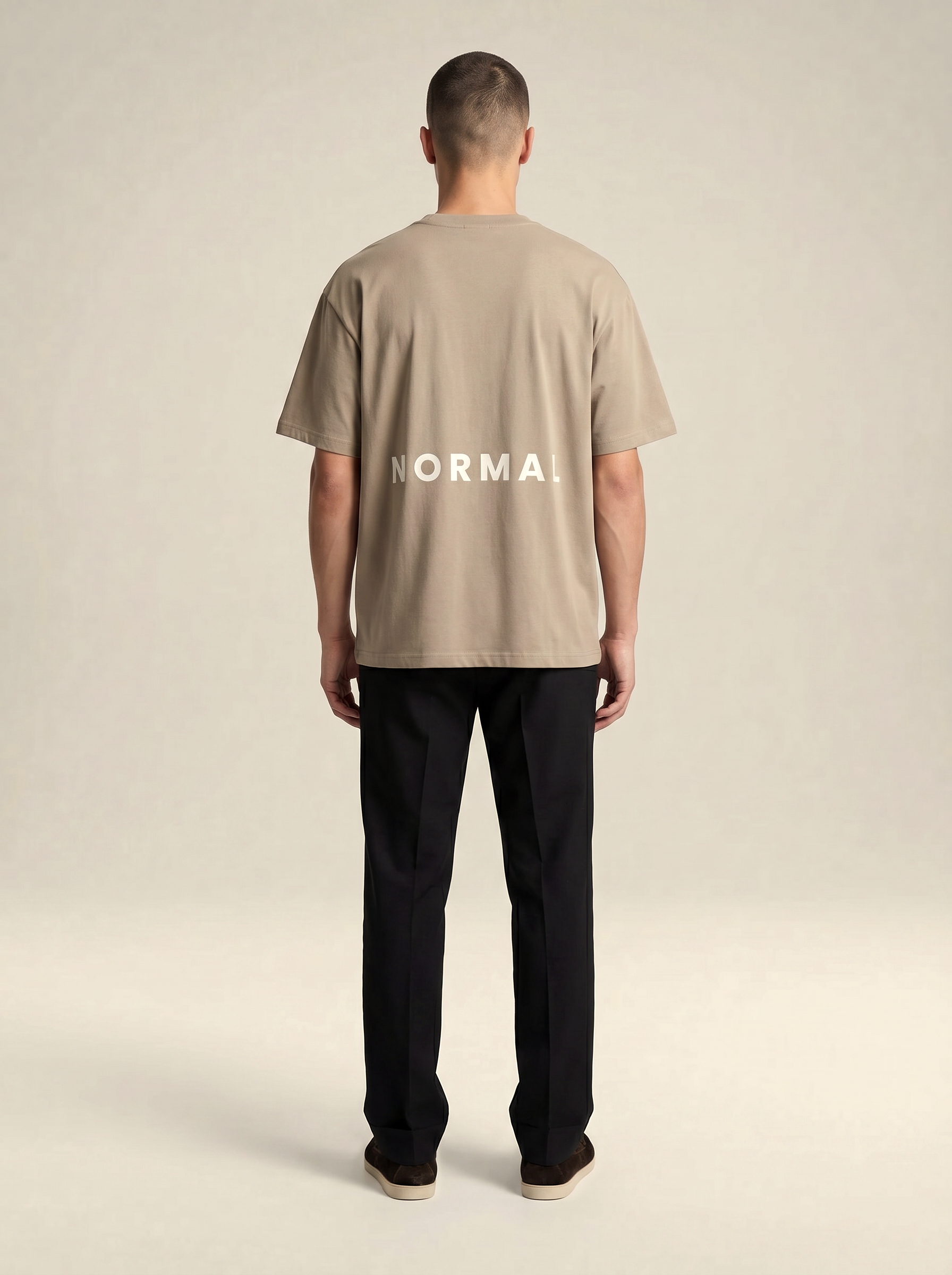 Model wearing Brenton Showcasing the back of the T-shirt with the word NORMAL print across the t-shirt.