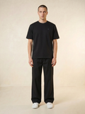 Person wearing a black t-shirt and black pants on a beige background