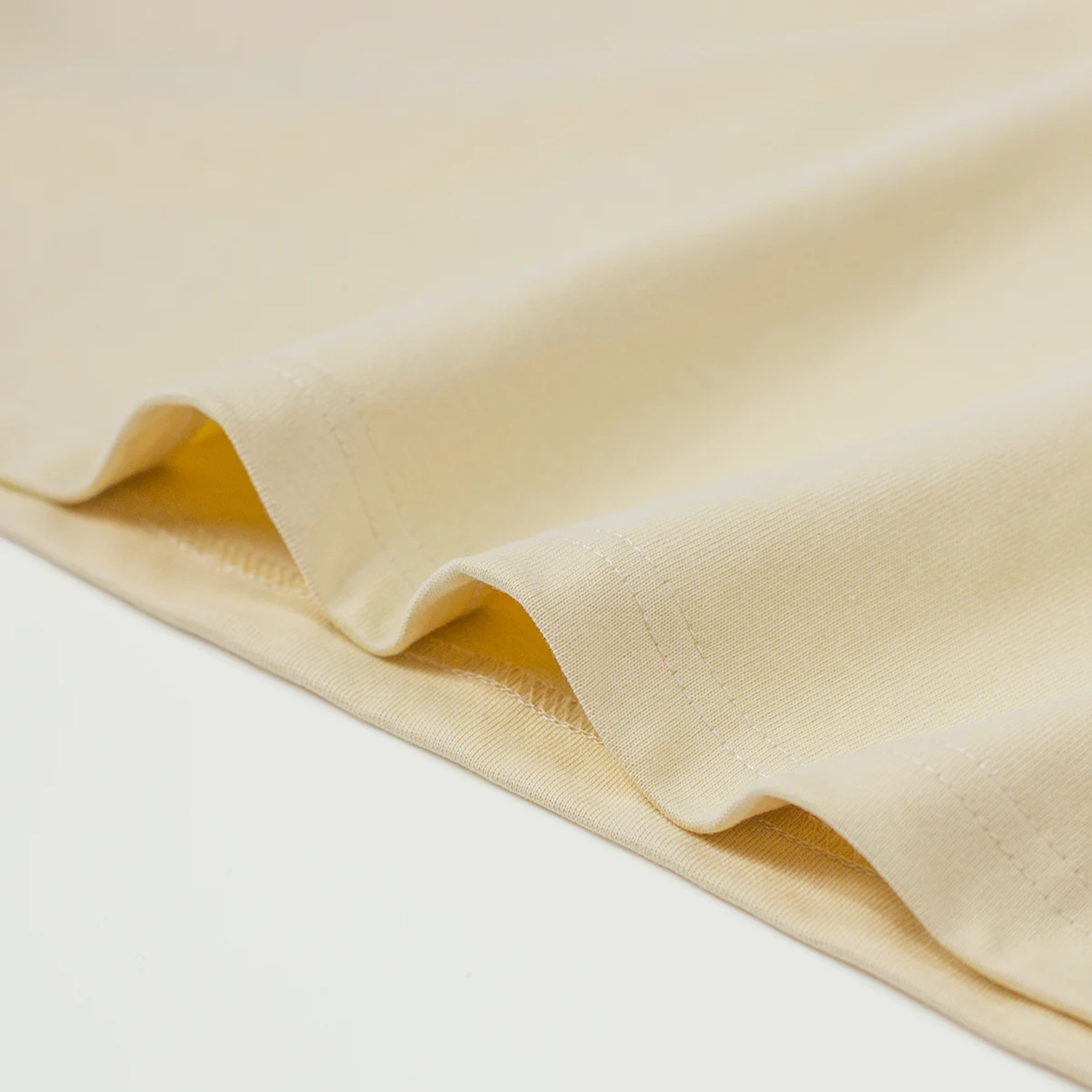 Close-up of light yellow fabric t-shirt on the edge with a soft texture on a light background