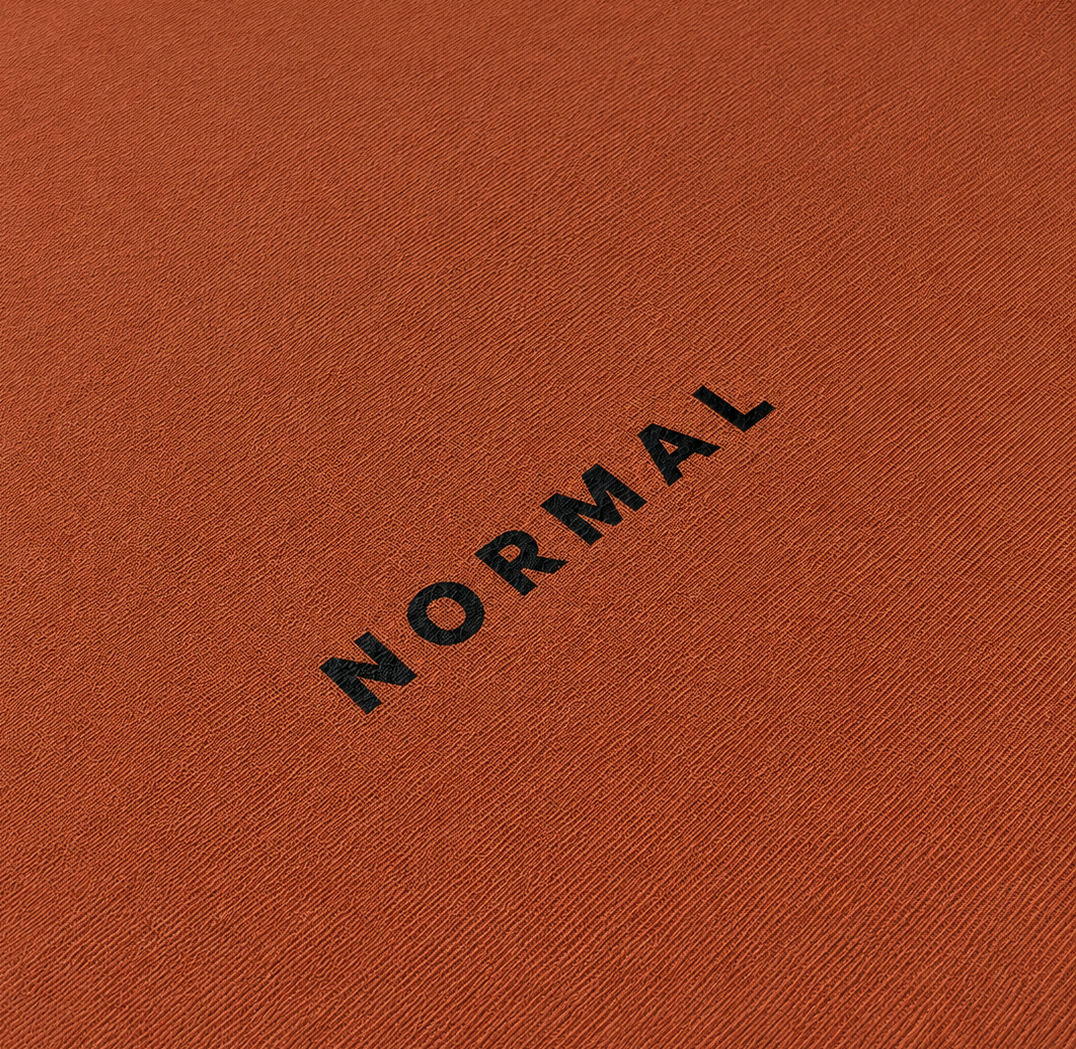 Text 'NORMAL' on the front of the t-shirt