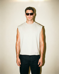 Man wearing a sleeveless white shirt and sunglasses against a plain background