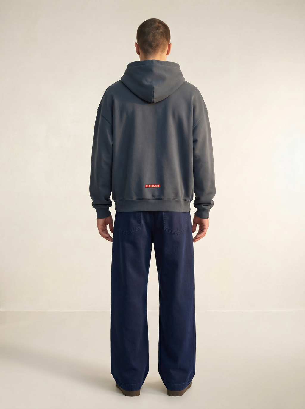 Person wearing a gray hoodie and navy pants on a white background