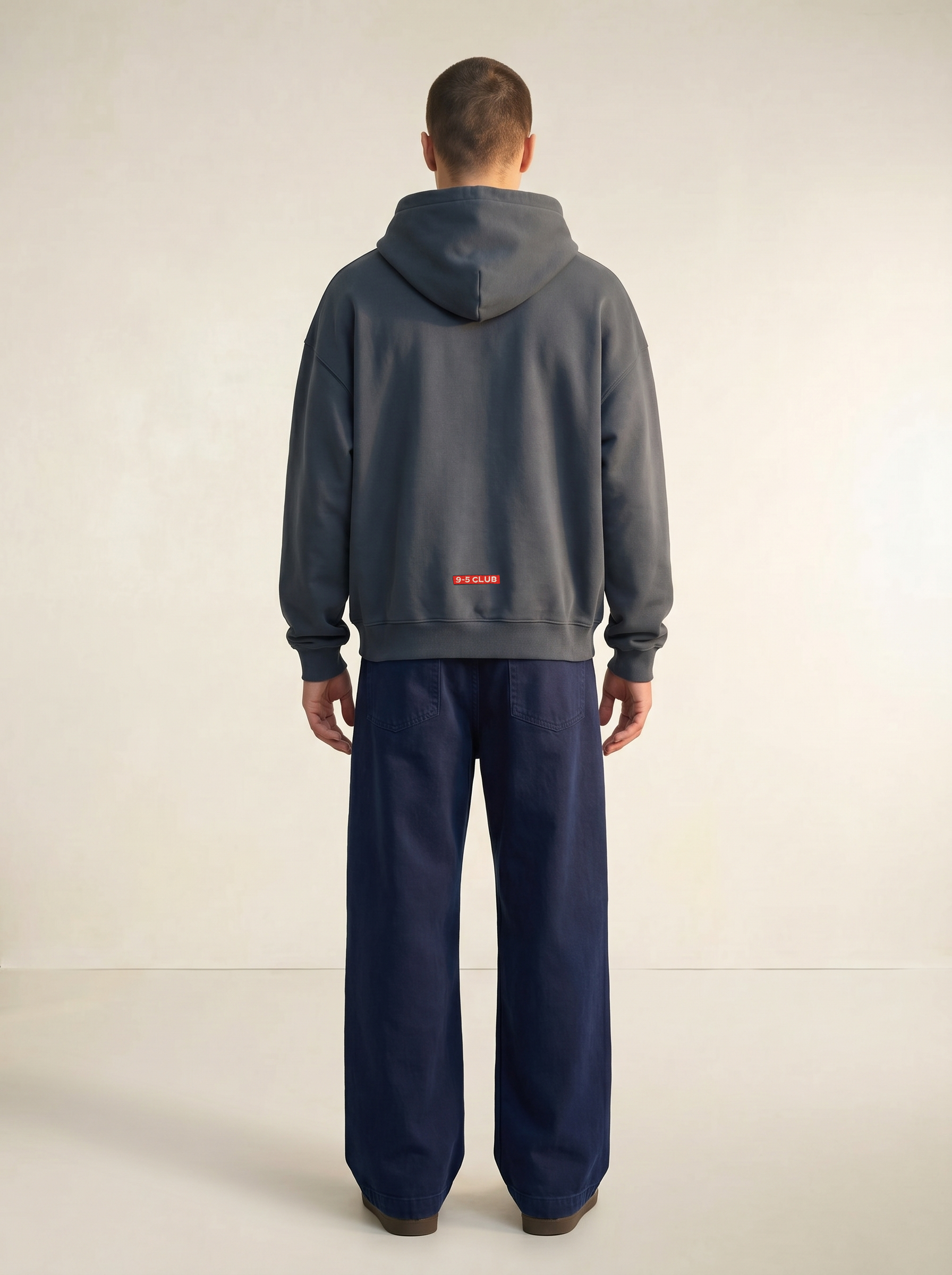 Person wearing a gray hoodie and navy pants on a white background