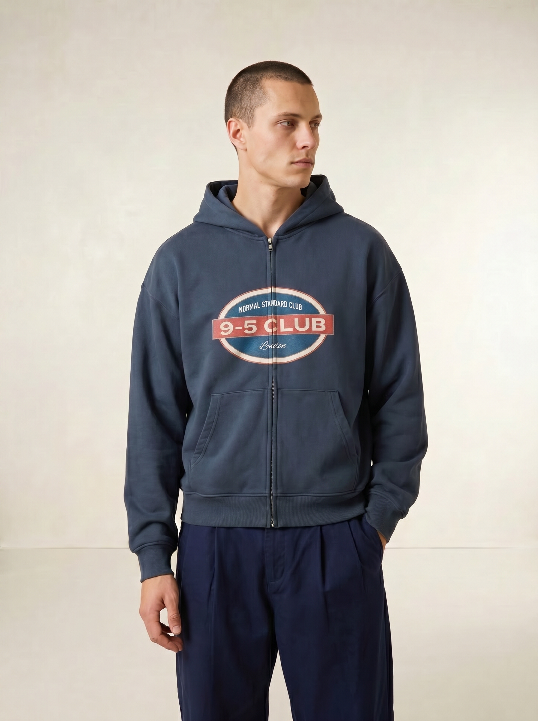 Man wearing a navy blue hoodie with a logo on a plain background
