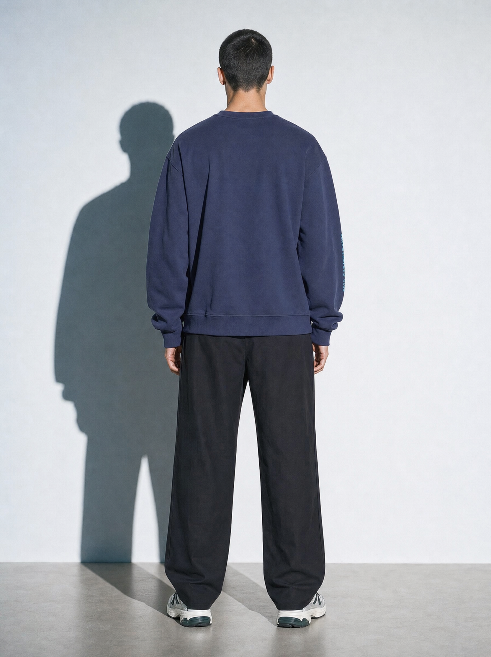 Model is wearing Normal Standard 9-5 Club navy sweatshirt and showcasing the back of the sweatshirt.
