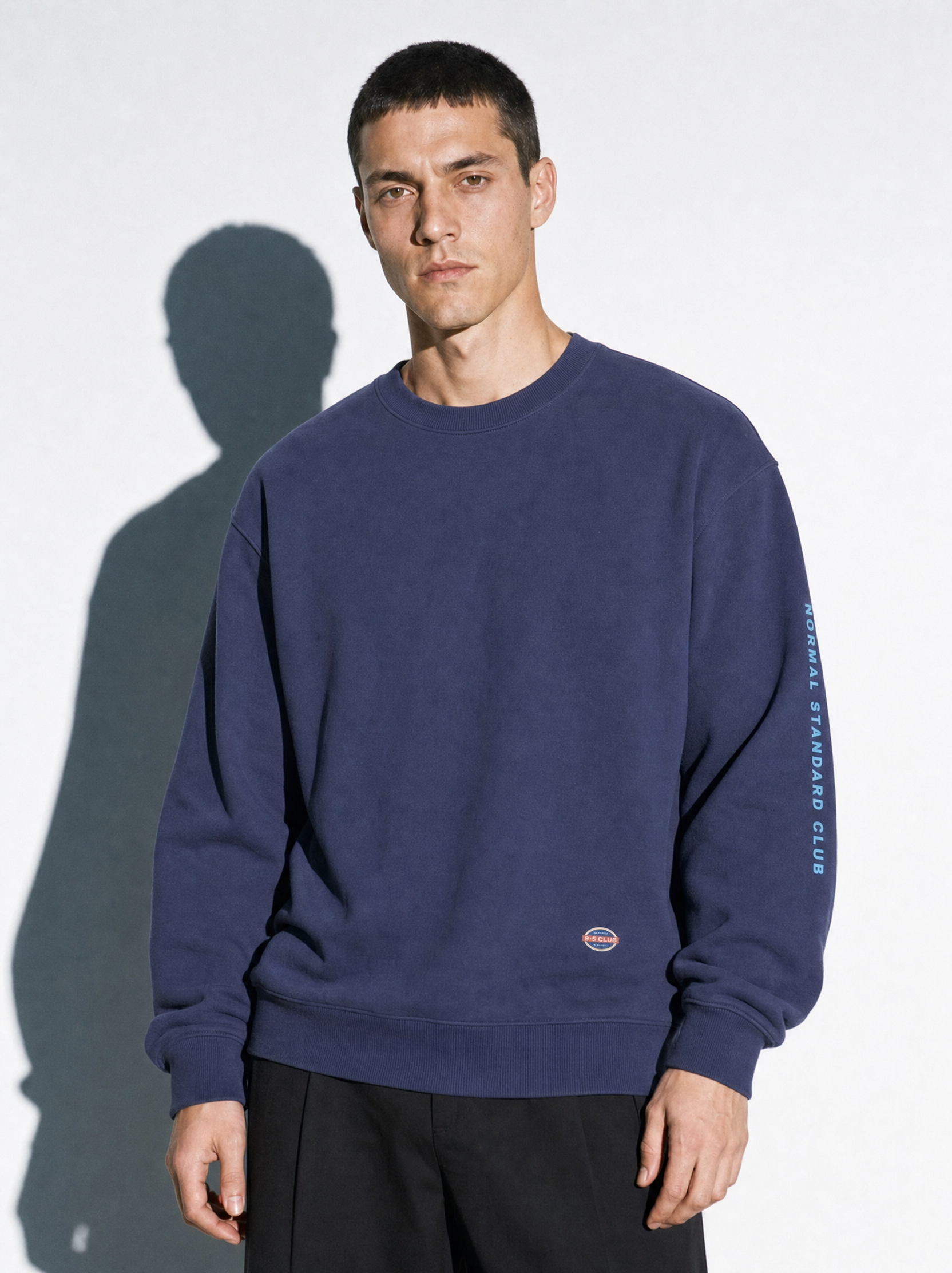 Model is wearing Normal Standard 9-5 Club navy sweatshirt.